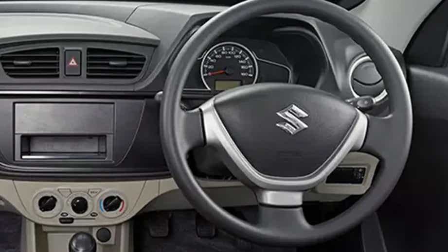 dashboard and steering wheel of a Solid White Maruti Suzuki Alto Tour