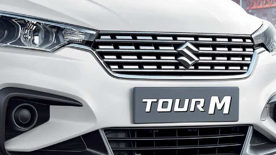 Front grille and headlight view of a Pearl Arctic White Maruti Suzuki Ertiga Tour