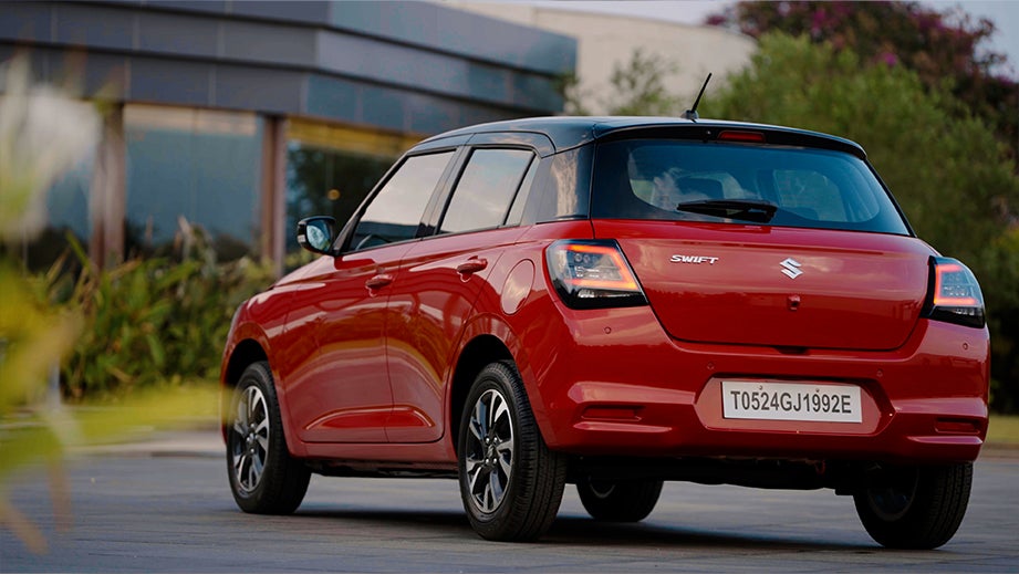 rear three-quarter of a Sizzling Red with Midnight Black Maruti Suzuki Swift