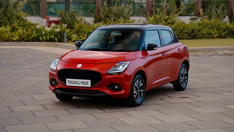 front three-quarter of a Sizzling Red with Midnight Black Maruti Suzuki Swift
