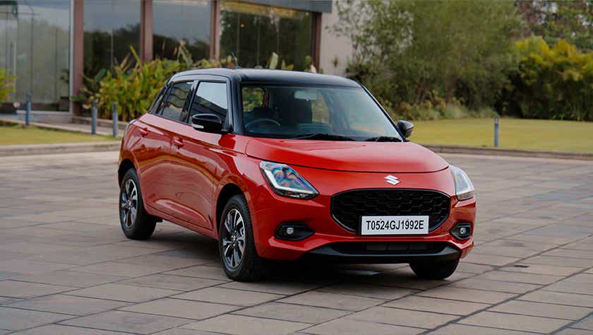 front three-quarter view of a Sizzling Red with Midnight Black Maruti Suzuki Swift