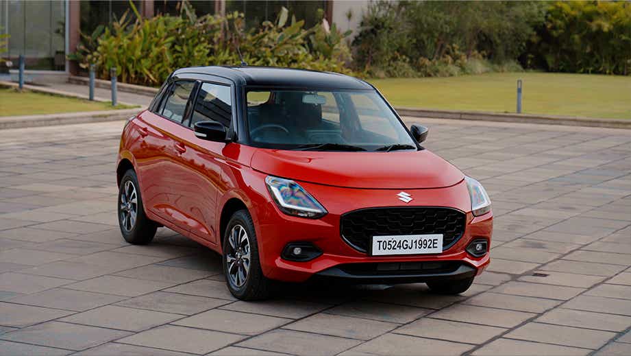 Front three-quarter view of a Sizzling Red with Midnight Black Maruti Suzuki Swift