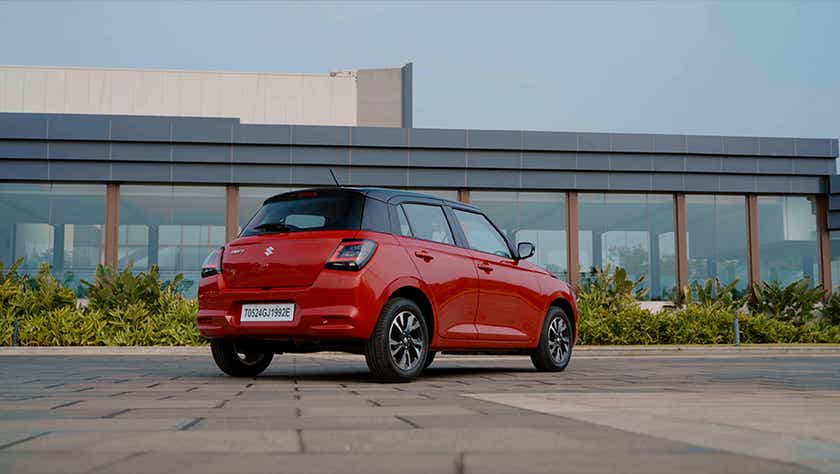 rear three-quarter of a Sizzling Red with Midnight Black Maruti Suzuki Swift