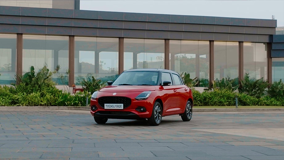 front three-quarter view of a Sizzling Red with Midnight Black Maruti Suzuki Swift