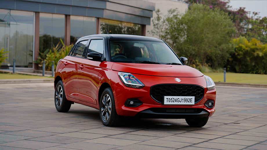 front three-quarter view of a Sizzling Red with Midnight Black Maruti Suzuki Swift