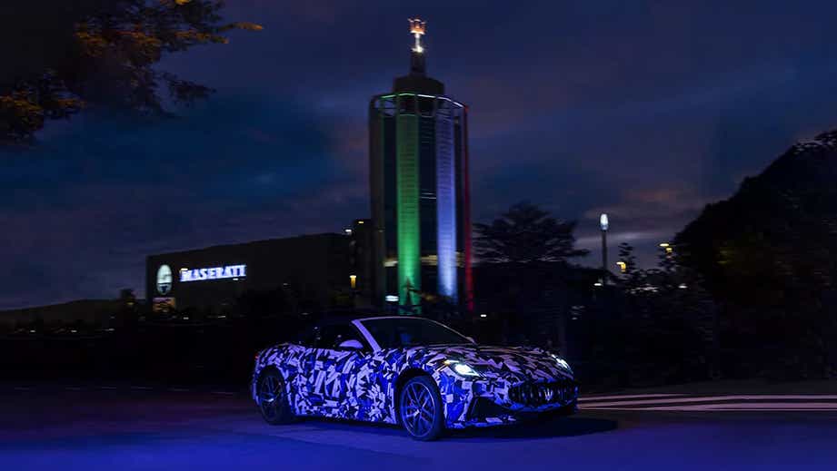 Front view of a Maserati GranCabrio at night near a lit tower