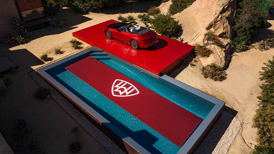 Overhead view of a Garnet Red Metallic Mercedes-Benz Maybach SL 680 convertible parked beside a luxury pool