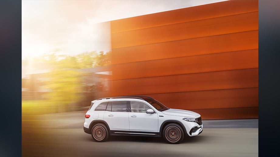 side view of a Mercedes-Benz EQB 2022-23 driving past an orange building