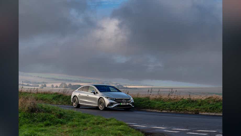 front three-quarter view of a Mercedes-Benz EQS on a rural road