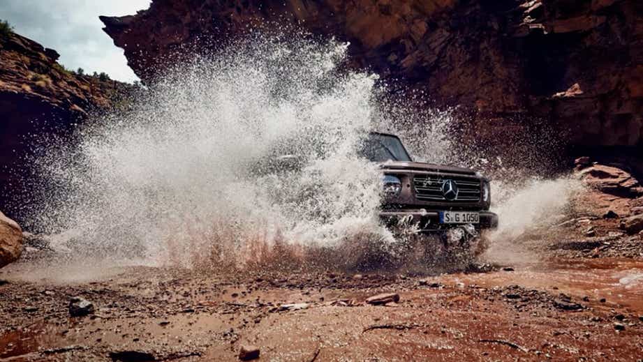 Front view of a Polar White Non Metallic Mercedes-Benz G-Class splashing through water