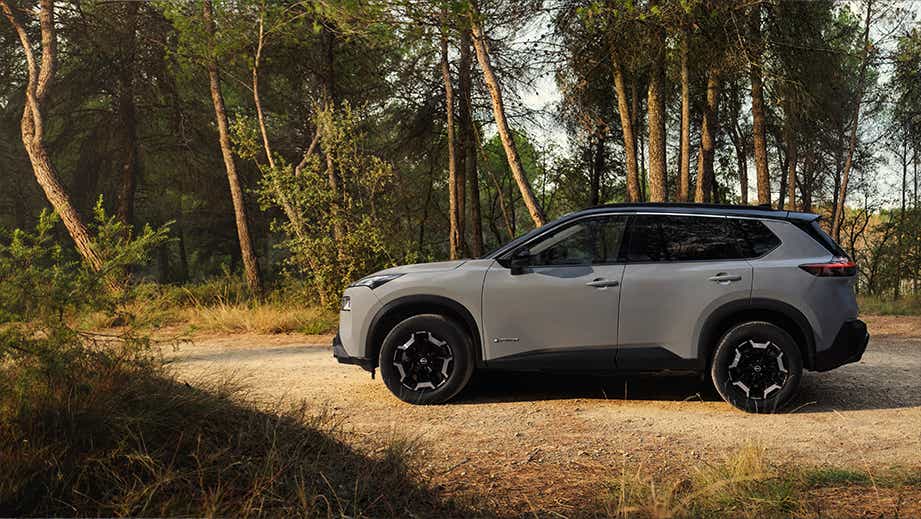 profile view of a Nissan X-Trail SUV in a wooded area