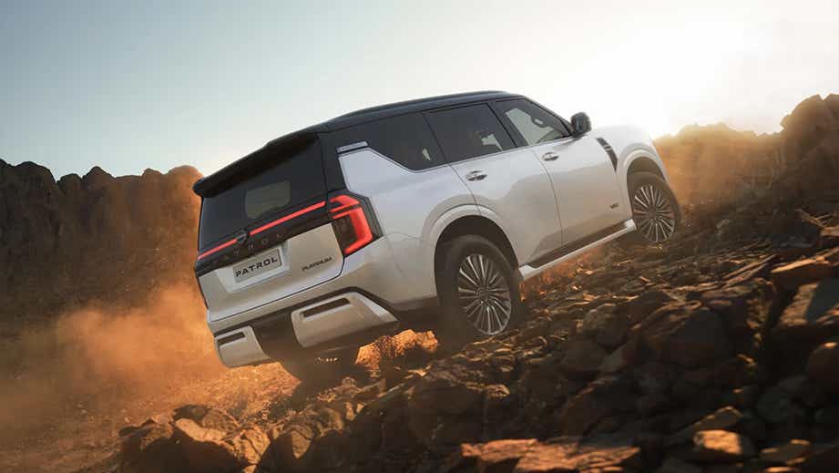 Rear three-quarter view of a Nissan Patrol Platinum climbing rocky terrain