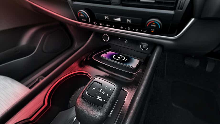 Interior center console of a Nissan X-Trail showing gear selector and wireless charging pad