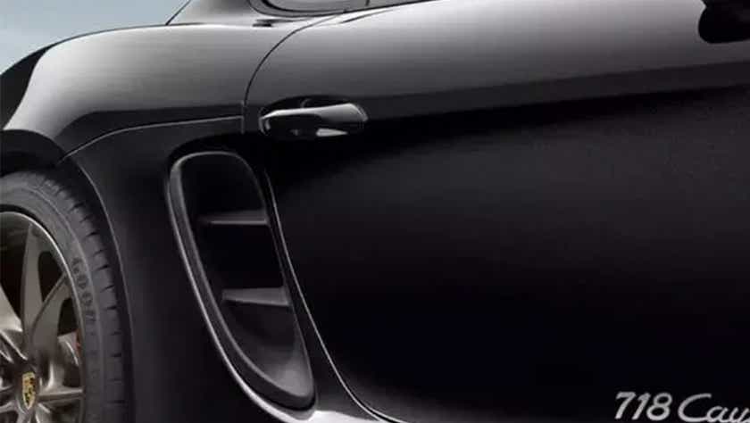 Close-up of the rear fender and side vent of a Jet Black Metallic Porsche 718