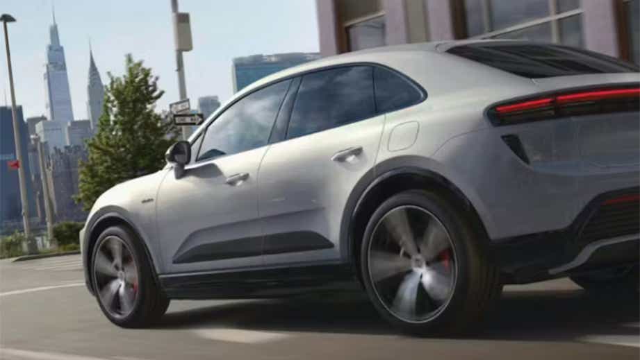 rear three-quarter view of a Porsche Macan EV driving in city