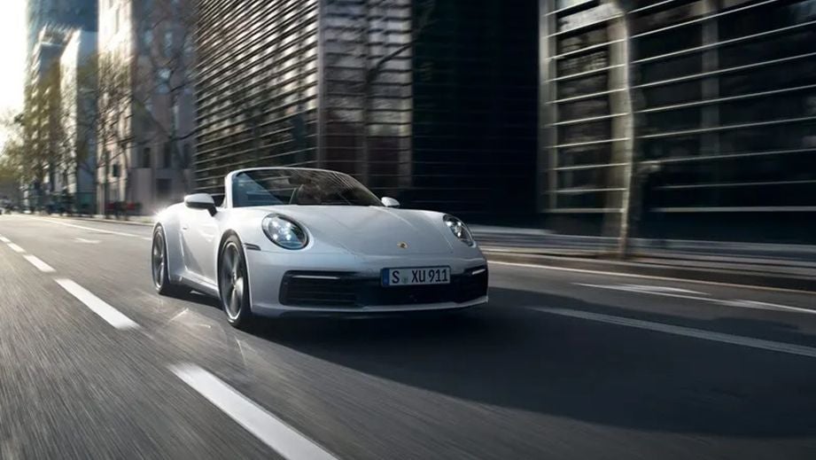 front view of a Porsche 911 convertible driving on a city street