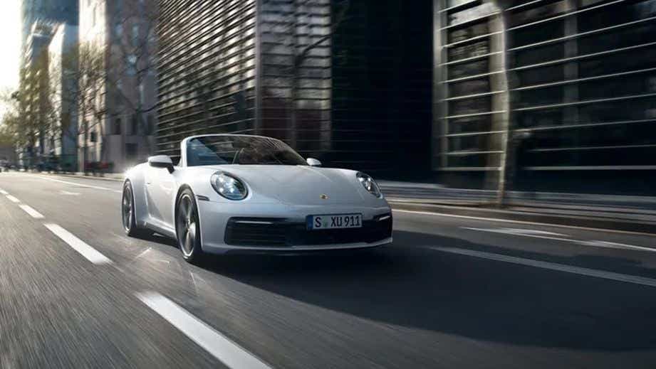 front view of a Porsche 911 convertible driving on a city street