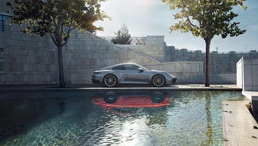 side view of a Porsche 911 beside a reflective pool