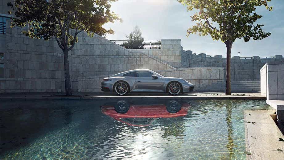 side view of a Porsche 911 beside a reflective pool