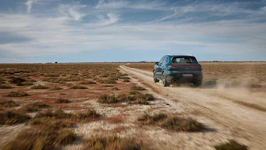 rear view of a Porsche Cayenne driving on a dirt road