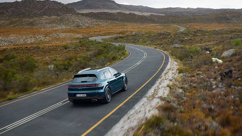 rear three-quarter view of a Porsche Cayenne driving on a winding road