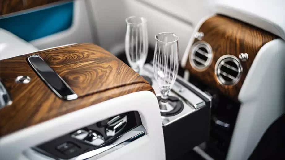 rear seat interior with wood trim and champagne flutes of a Rolls-Royce Cullinan
