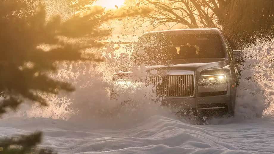 Front view of a Rolls-Royce Cullinan driving through snow