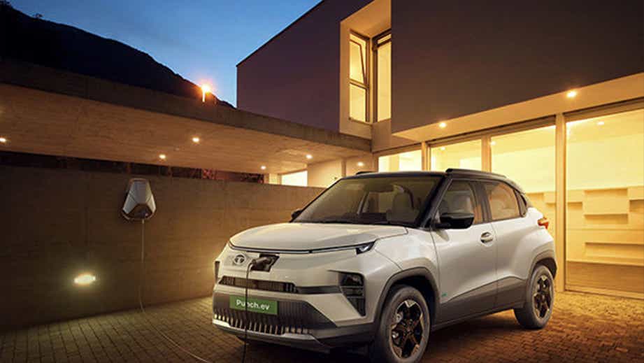 Front three-quarter view of a Pristine White Dual Tone Tata Punch EV charging at a modern home