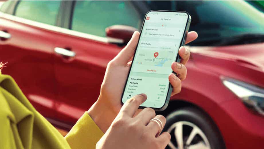 Person using smartphone with connected features near a Sportin Red Toyota Glanza