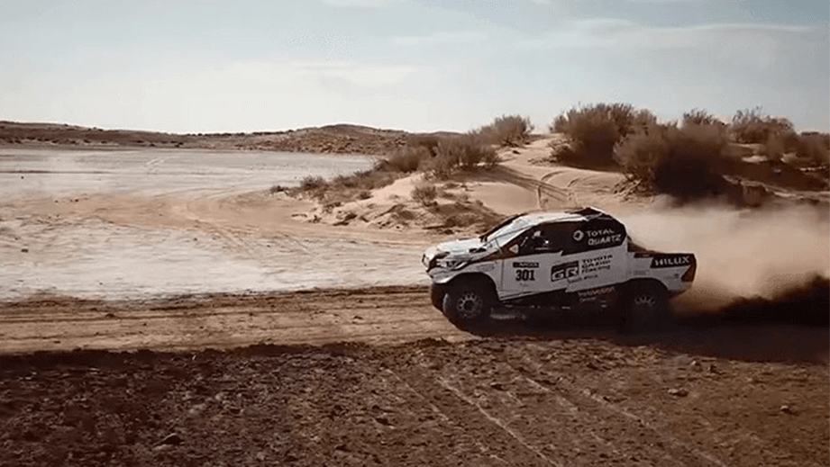 Side view of a Toyota Hilux rally truck driving on a dirt track