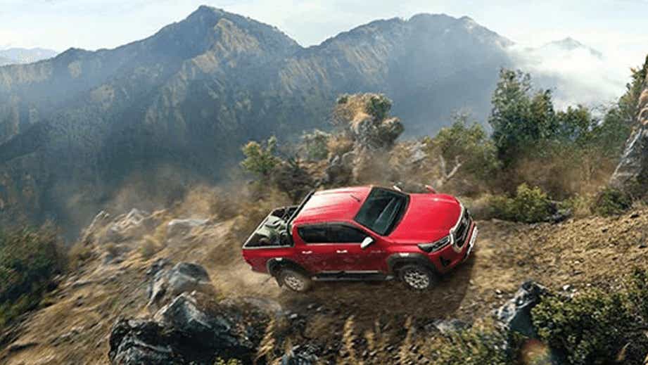 full-car view of an Emotional Red Toyota Hilux on a rugged mountain trail
