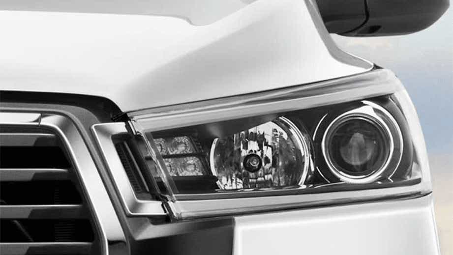 Headlight close-up of a Platinum White Pearl Toyota Innova Crysta