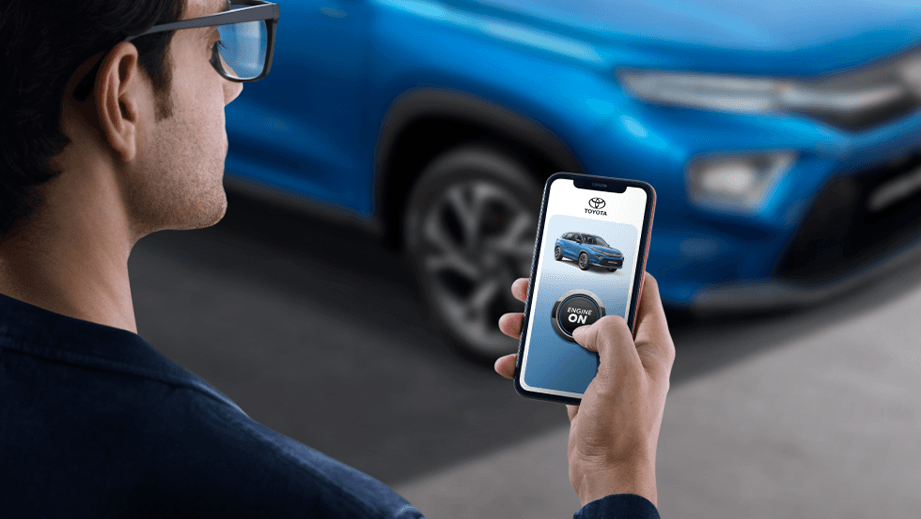 Man using a smartphone to start a Toyota Urban Cruiser Hyryder parked nearby