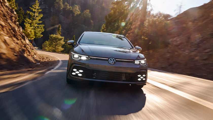 Front view of a Volkswagen Golf GTi driving on a mountain road