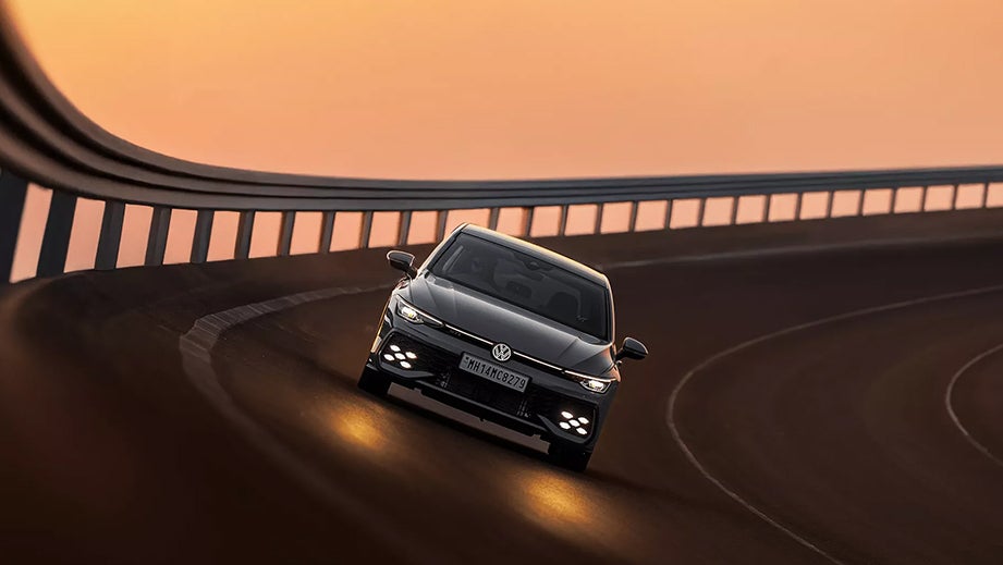 front view of a Volkswagen Golf GTi on a banked road at sunset