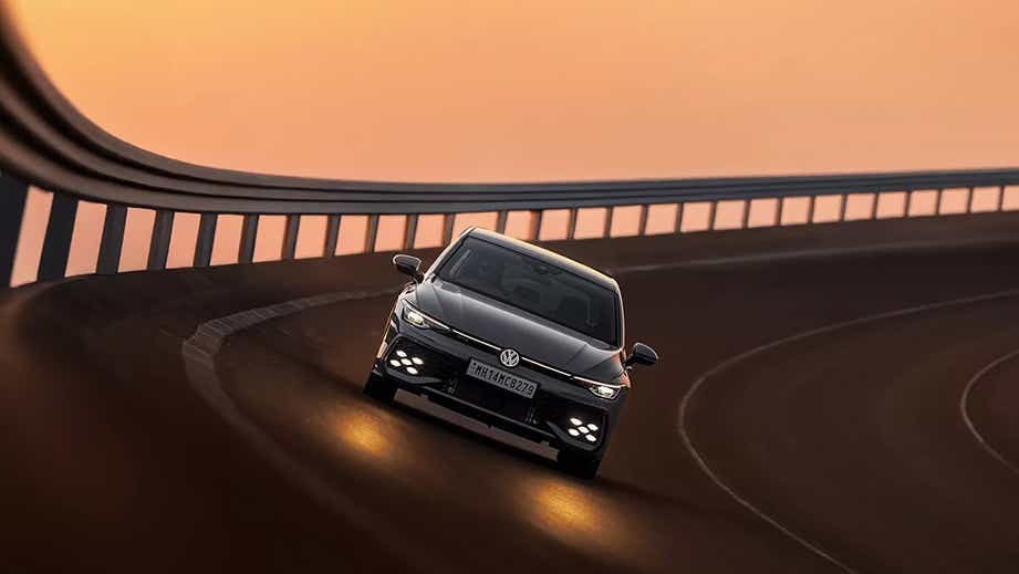 front view of a Volkswagen Golf GTi on a banked road at sunset