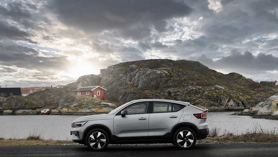profile view of a Volvo C40 Recharge by a rocky lake landscape