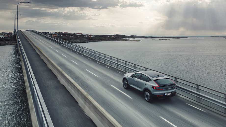 Rear three-quarter view of a Volvo C40 Recharge driving on a coastal bridge