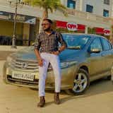 Front three-quarter view of a Honda City with a person leaning on the car
