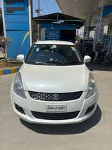 Front view of a Pearl Arctic White Maruti Suzuki Swift at a petrol station