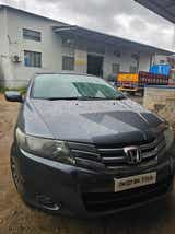 Front view of a Honda City near an industrial building