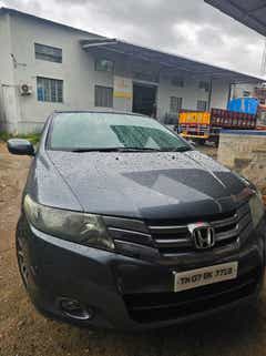 Front view of a Honda City near an industrial building