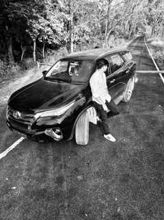 front three-quarter view of a Toyota Fortuner with a person leaning on the car