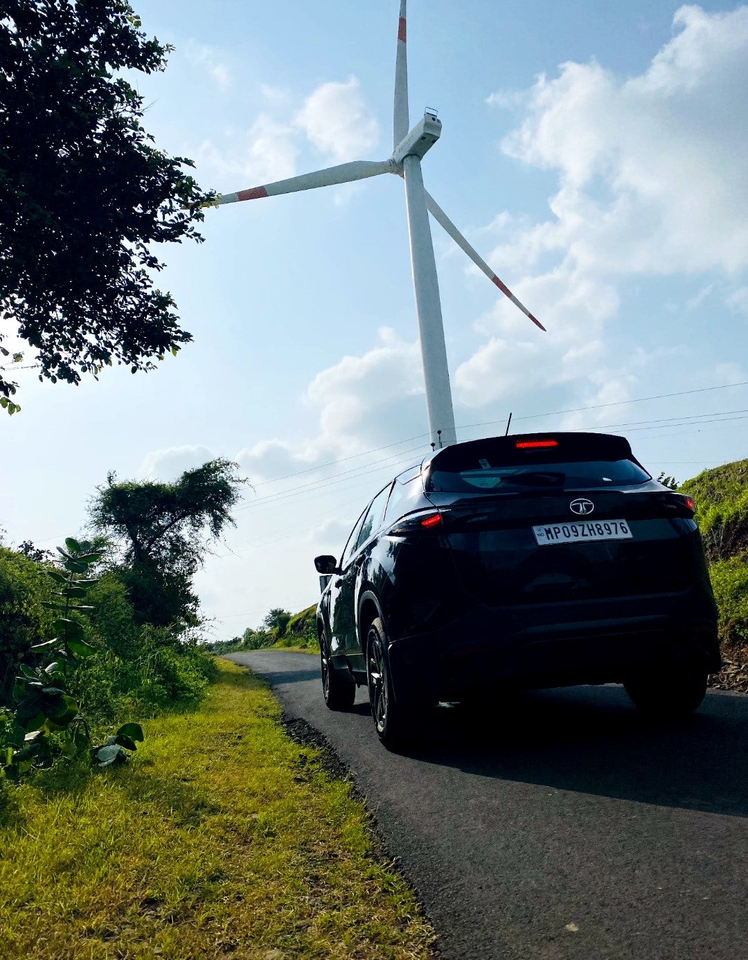 rear view of a Tata Harrier 2019-2023 on a rural road with a wind turbine