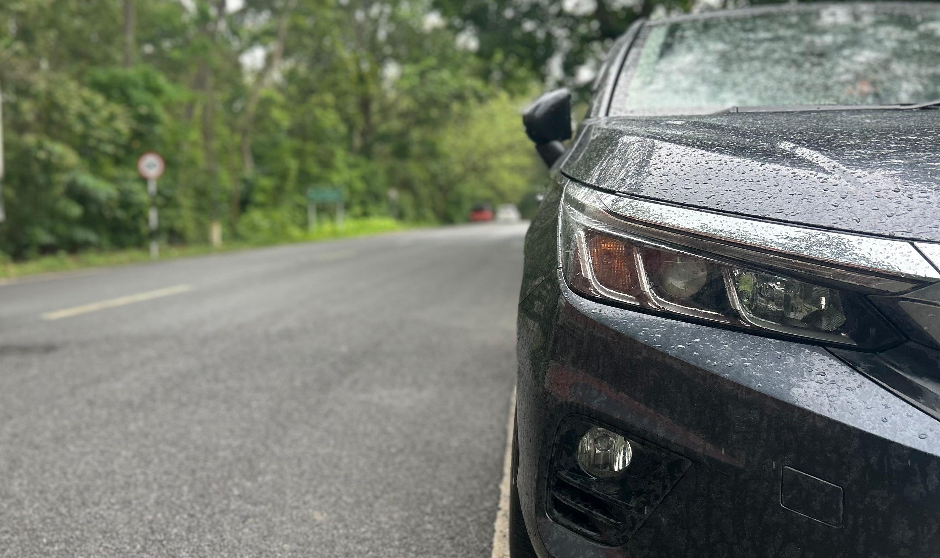 front headlight close-up of a Honda City on a wet road