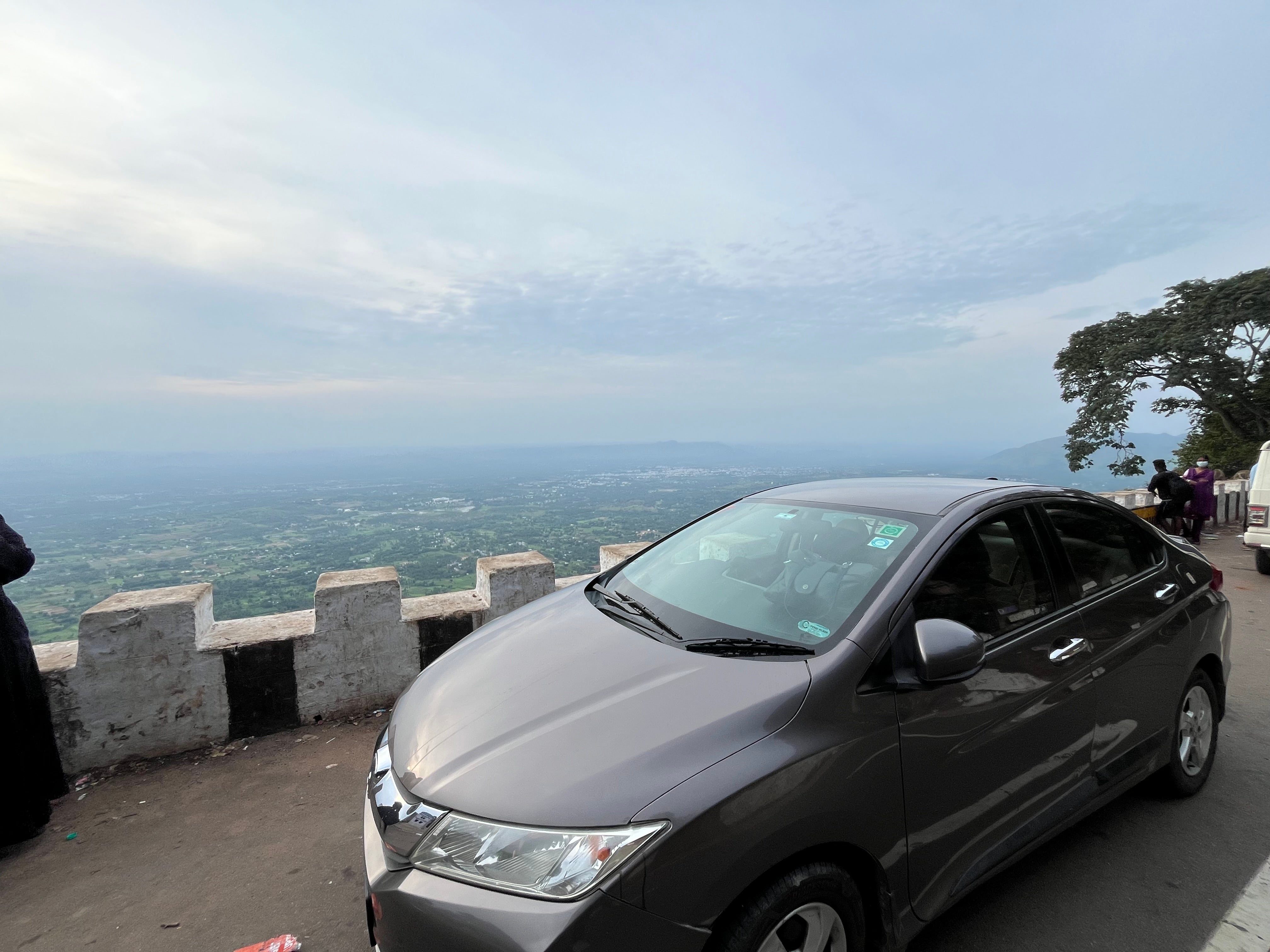 front three-quarter of a Honda City parked by a hill viewpoint