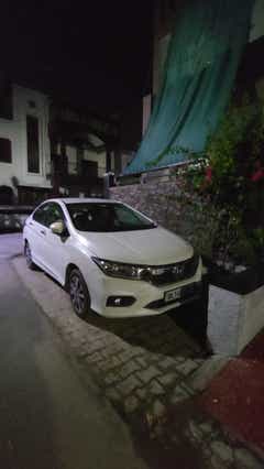 Front three-quarter view of a Honda City parked on a street at night