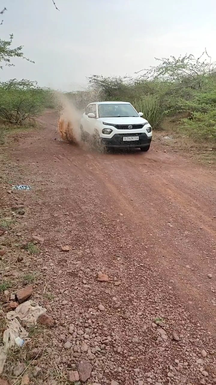 front view of a Orcus White Tata Punch driving on a dirt road