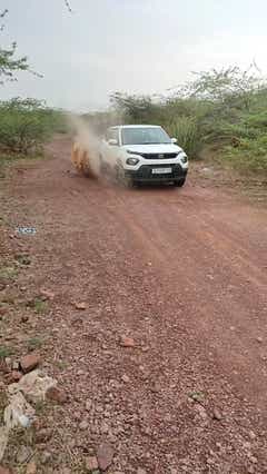 front view of a Orcus White Tata Punch driving on a dirt road