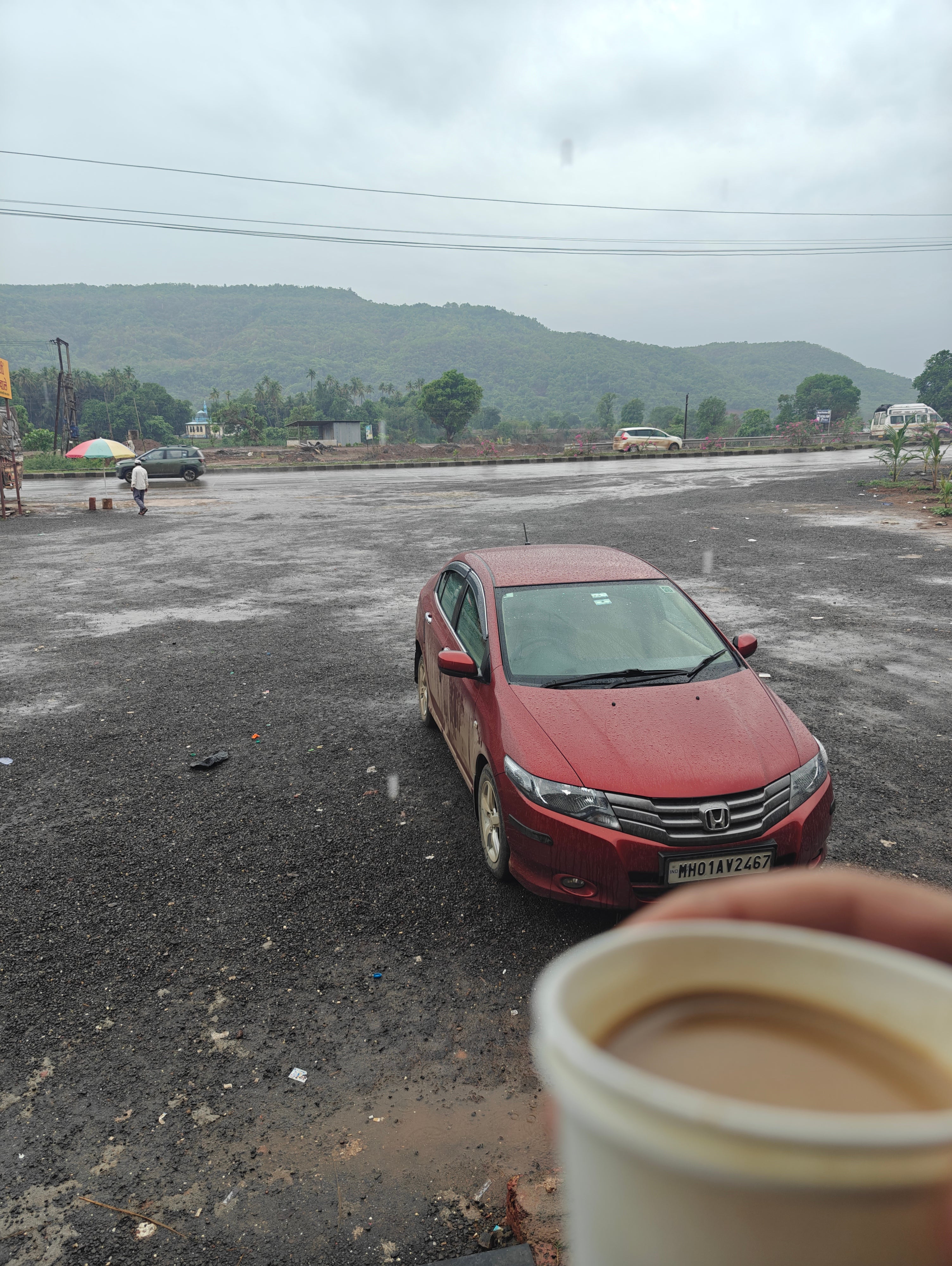front three-quarter view of a Honda City in an open parking lot on a rainy day